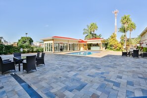 A poolside area with outdoor seating and a building with a red roof.