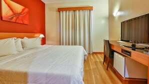 Een hotelkamer met een bed, een bureau met een televisie en een raam met gordijnen.
