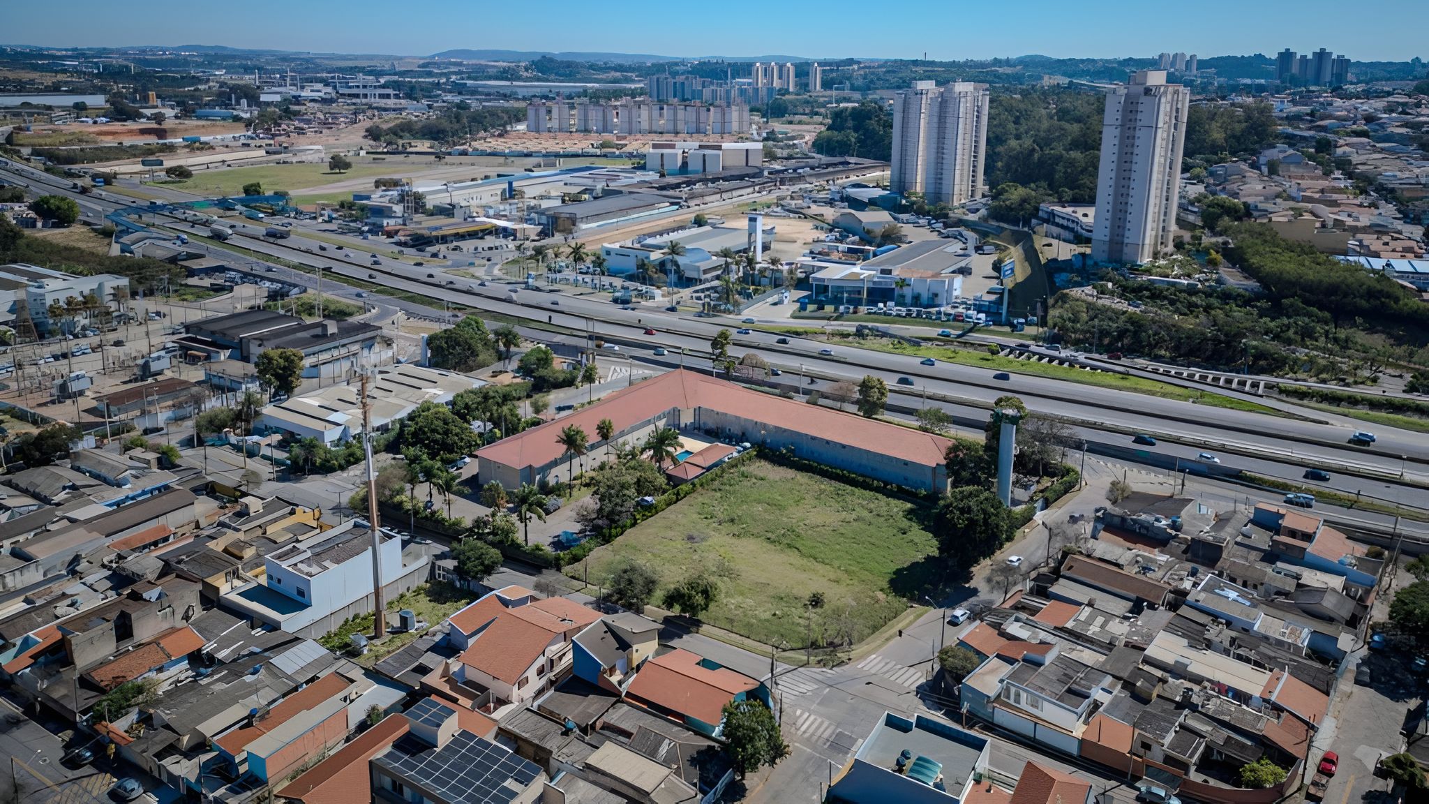 Vista aérea de um horizonte urbano com mistura de edifícios residenciais e comerciais, incluindo apartamentos altos e estruturas industriais.