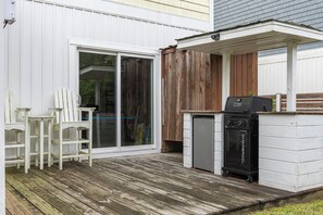 Eine Terrasse mit Grill, Kühlschrank und Stuhl.