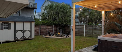 A backyard with a hot tub, a fire pit, and outdoor seating.