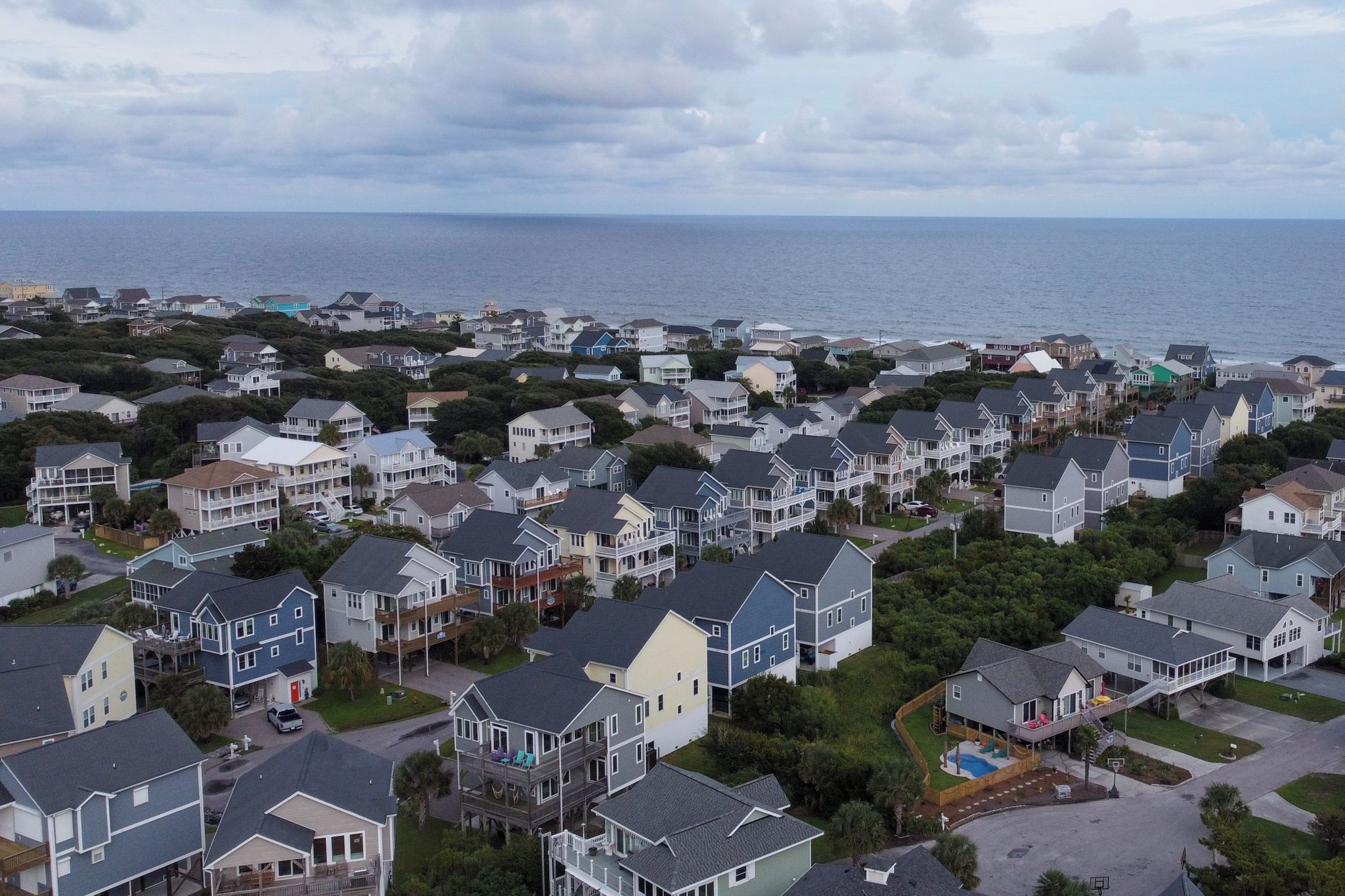 A coastal residential area with houses, some with balconies, and a view of the sea.