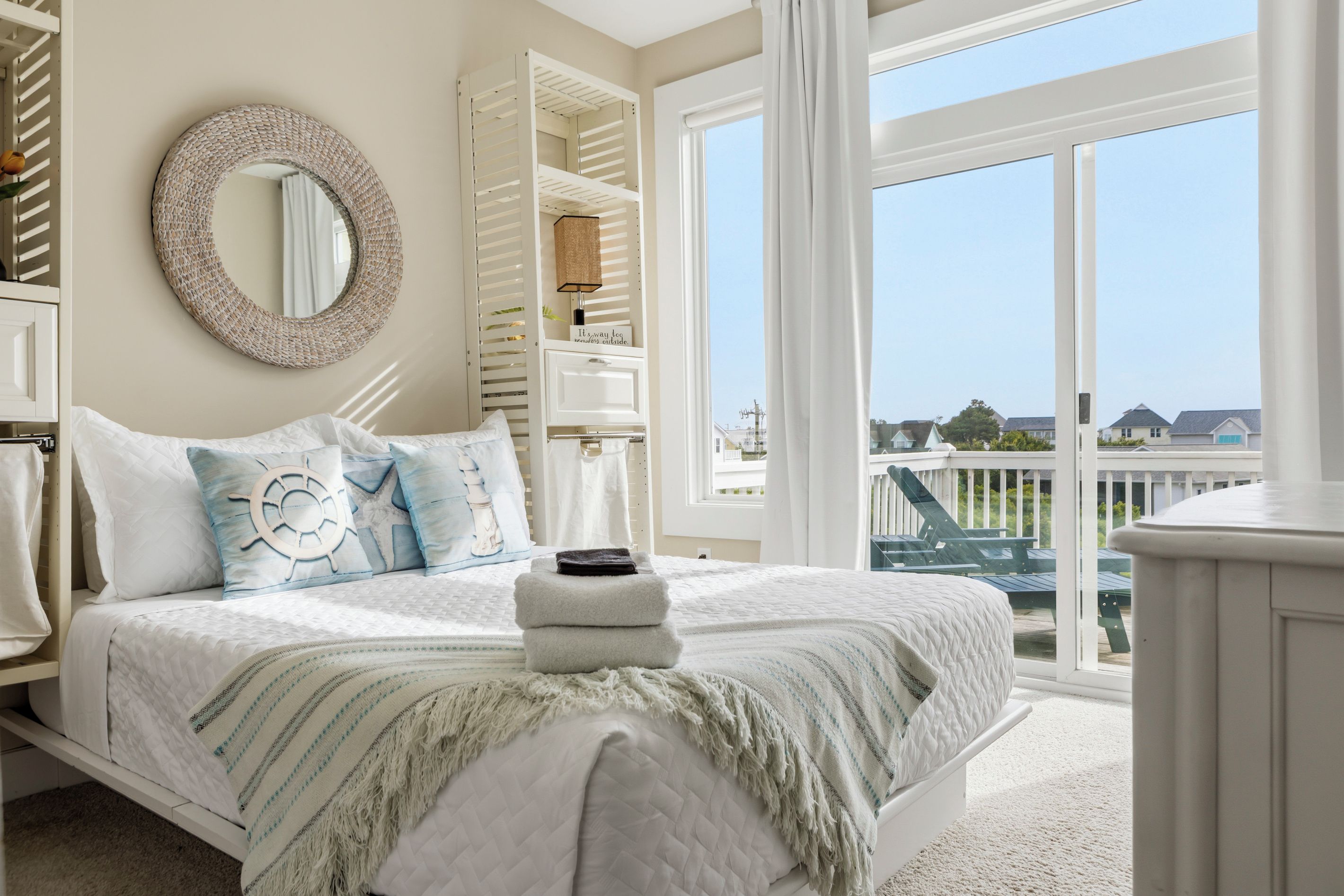 A bedroom with a bed, a circular mirror, a wardrobe, and a view of the outside.