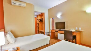 Hotellihuone, jossa on kaksi erillistä sänkyä, työpöytä tuolilla, televisio ja vaatekaappi.