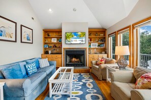A living room with a fireplace, sofas, a coffee table, and a TV. - Turtle's Cove Corolla retreat with beach access, hot tub, and views. (Corolla)