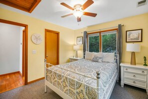 A bedroom with a bed, bedside tables, a ceiling fan, and a window with curtains. - Turtle's Cove Corolla retreat with beach access, hot tub, and views. (Corolla)