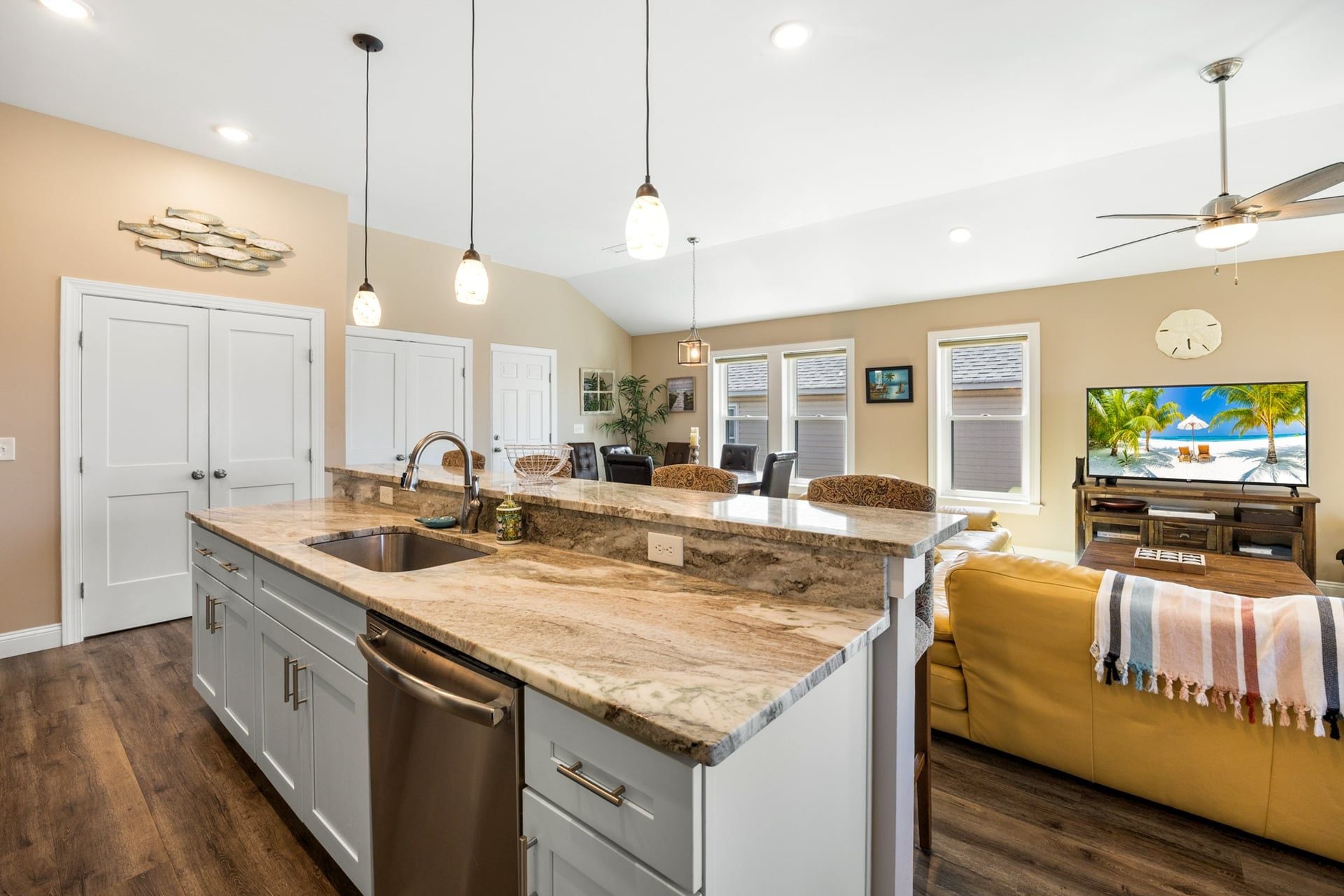 A kitchen with a marble countertop, stainless steel appliances, and pendant lighting.