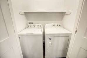 Een kleine wasruimte met twee Whirlpool wasmachines en een droger.