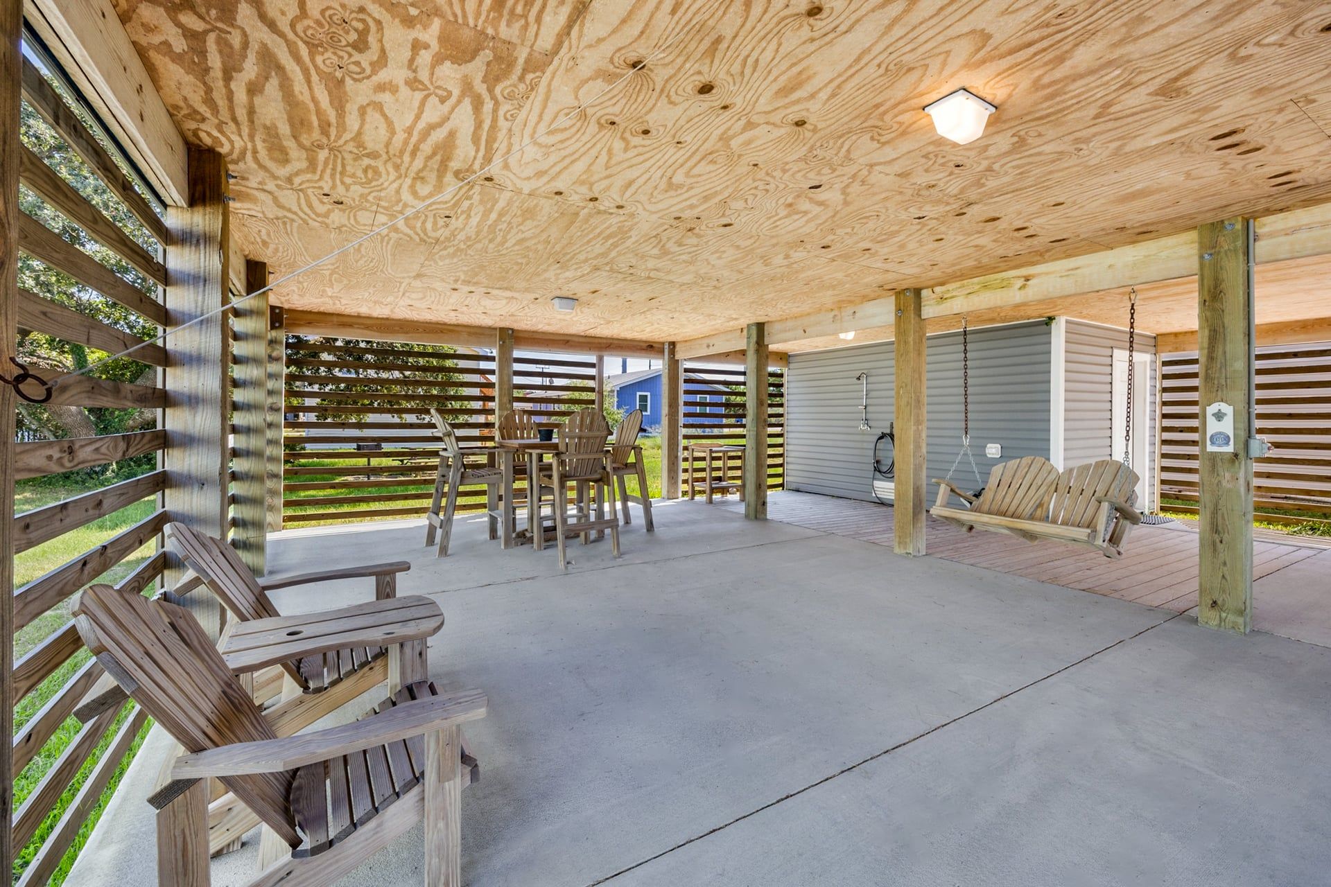 Un patio al aire libre con techo de madera, una mesa con sillas y una hamaca.