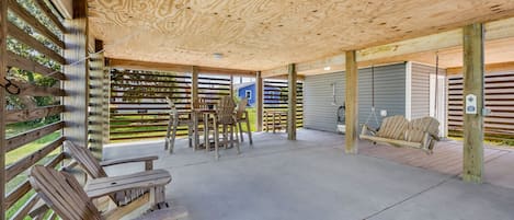 Un patio al aire libre con techo de madera, una mesa con sillas y una hamaca.