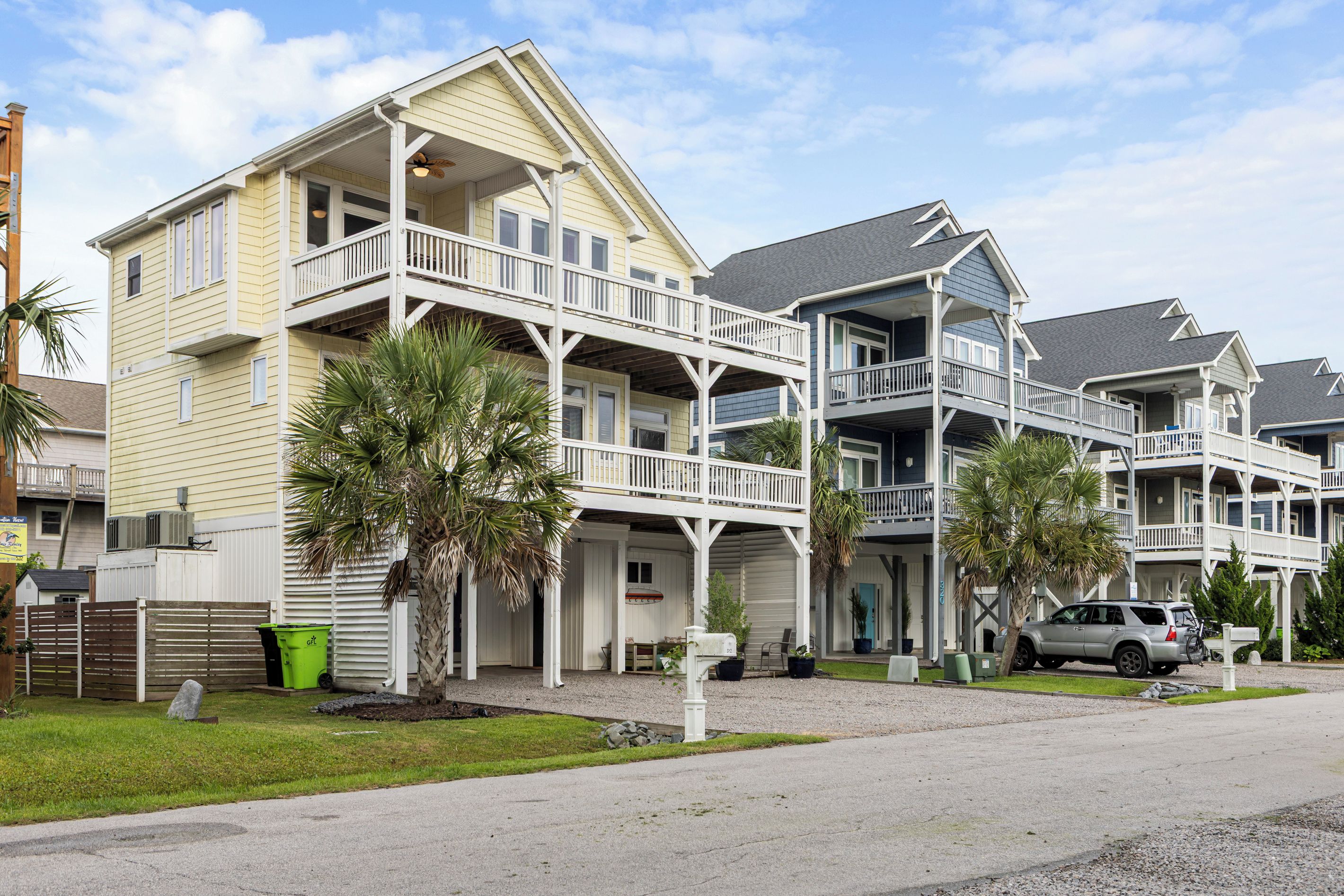 A beachfront hotel with multiple balconies, a covered outdoor seating area, and a parking lot.