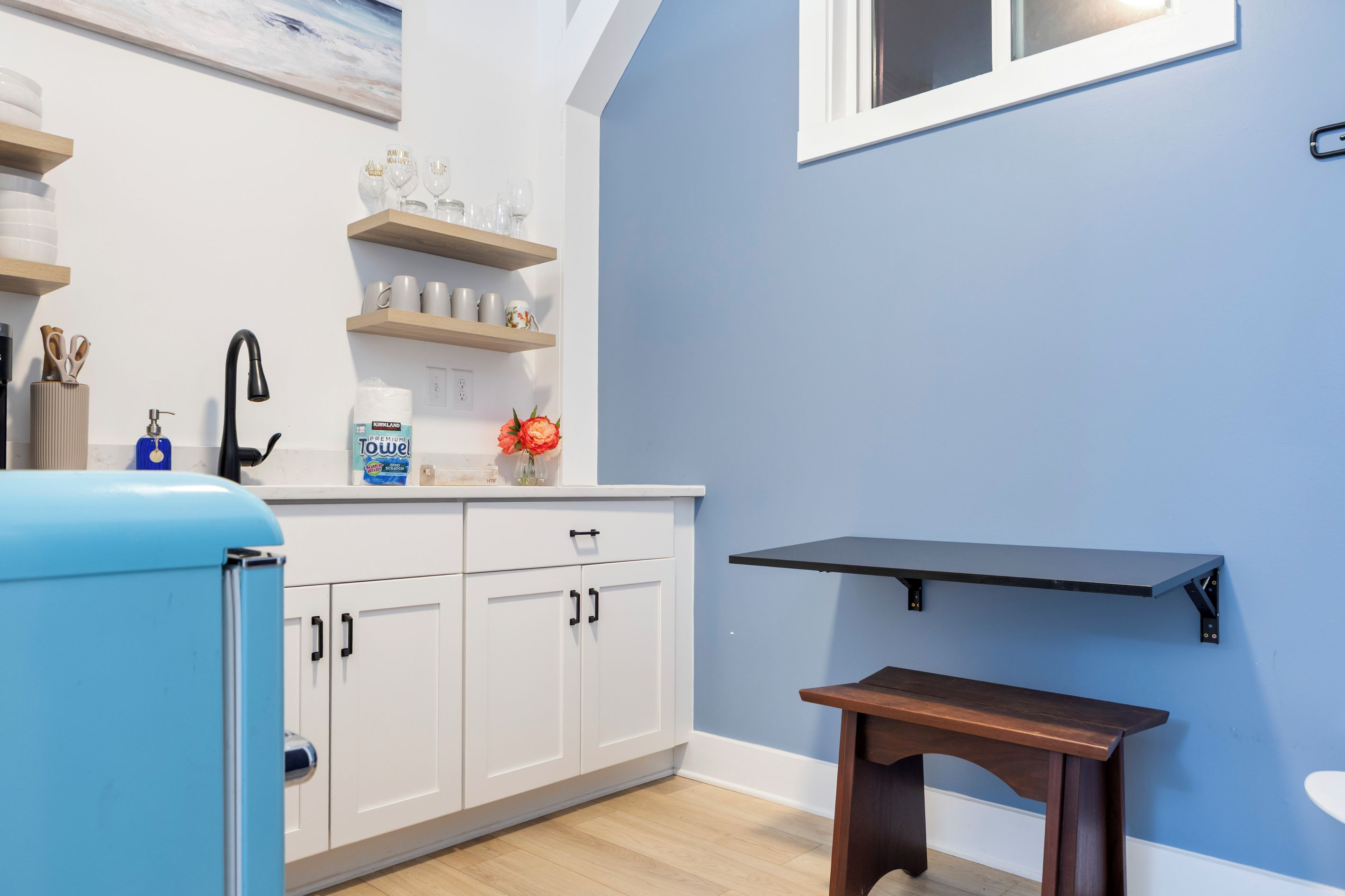 Een keuken met witte kasten, een blauwe koelkast en een houten tafel.