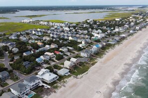 A coastal residential area with houses along the beach, a road, and a bridge in the distance. - Sand Before Time · Cozy Studio Apt, Steps to Beach (Surf City)