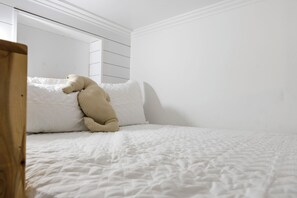 A bedroom with a bed, a white wall, and a wooden headboard. - Sand Before Time · Cozy Studio Apt, Steps to Beach (Surf City)