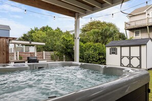 Ein Whirlpool unter einer Holzpergola mit Garten, inklusive Grillplatz und Gartenhaus.