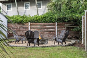 Zona relax esterna con un braciere in pietra e quattro poltrone Adirondack.