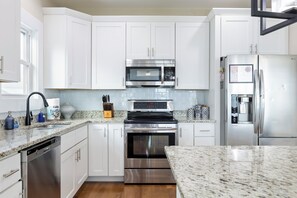 Una cucina moderna con mobili bianchi, elettrodomestici in acciaio inossidabile e ripiani in granito.