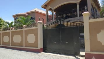 Una proprietà residenziale recintata con un portico coperto e un vialetto.