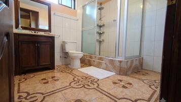 Une salle de bain équipée d’une douche, de toilettes, d’un lavabo et de carreaux de sol à motifs.