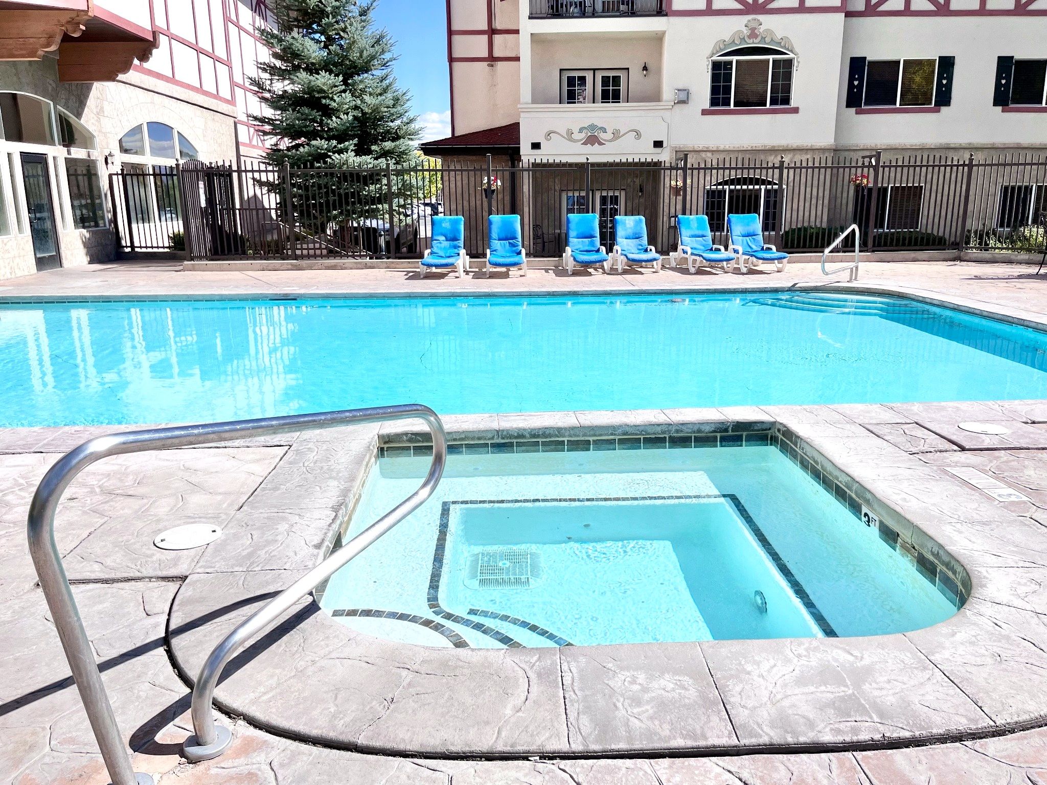 A swimming pool with a diving board and lounge chairs.