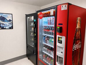 Una macchina distributrice automatica con il logo Coca-Cola, una scelta di bevande e una bottiglia di Coca-Cola.