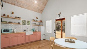 Una cocina con armarios rosa, un refrigerador blanco y techo de madera.