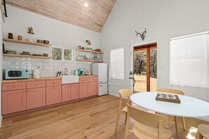 A kitchen with pink cabinets, a white refrigerator, and a wooden ceiling.