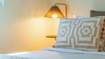 A bed with a patterned pillow and a lamp in the background.