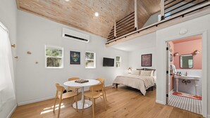 Una habitación con una cama, una mesa con sillas, un televisor y una ventana.
