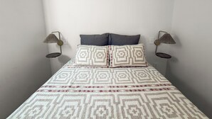 Een bed met beddengoed met een patroon, twee kussens en twee wandlampen.