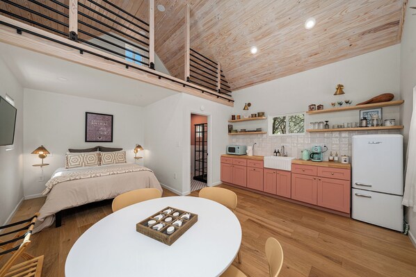 A modern kitchen with pink cabinets, a white refrigerator, and a dining area with a round table.
