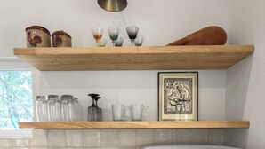 Een keuken met een witte koelkast, een houten aanrecht, een koffiezetapparaat, en een plank met glazen potten en een lijst met een foto.