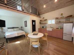 Une chambre d’hôtel de taille réduite, comprenant un lit, une table de chevet et une petite kitchenette.