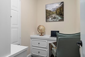 A study room with a desk, a globe, a laptop, a chair, and a framed landscape painting on the wall. - Gathering Oak | Cozy Fire Pit & Fall Getaway (Wimberly)