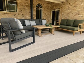 A covered outdoor seating area with a brick wall backdrop, a wooden table, and two sofas. - Harrowby Country House. New Magnesium Pool. Outdoor firepit. Sleeps 11. (Broke)