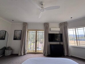 Ein Schlafzimmer mit einem Bett, einem Deckenventilator, einem Fernseher und Blick ins Freie.