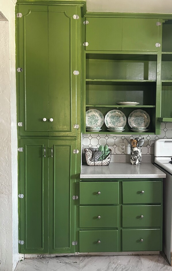 A kitchen with green cabinets, a countertop, and a tiled backsplash.