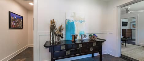 A hallway with a dark wooden console table, a painting, and a blue abstract painting on the wall.
