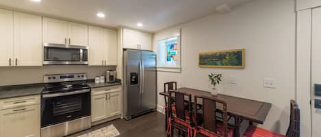 A modern kitchen with stainless steel appliances, a dining area with a table and chairs, and a window with a view.