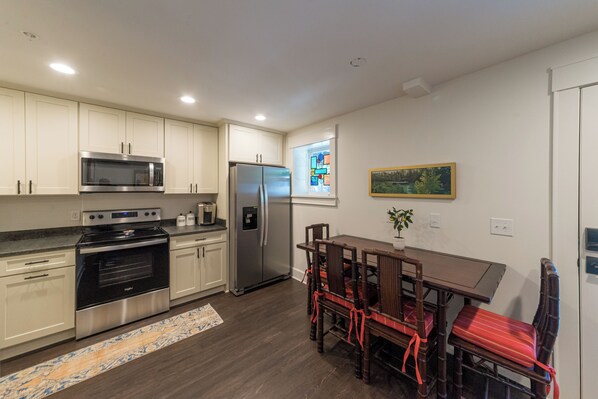 A modern kitchen with stainless steel appliances, a dining area with a table and chairs, and a window with a view.
