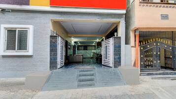 A building entrance with a gated driveway, a reception desk, and a staircase leading to the entrance.