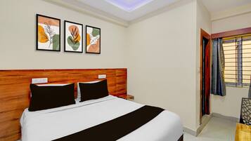 A hotel room with a bed, a wooden headboard, a nightstand, and a window with curtains.