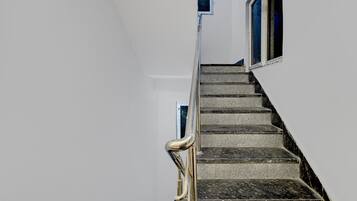 A staircase with a handrail, leading to a landing with a window.