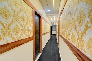 A hallway with patterned wallpaper and wooden trim, leading to a door with a sign. - Hotel O Gachibowli Crossway Hyderabad (Hyderabad)