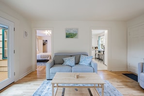 A modern living room with a grey sofa, a wooden coffee table, and a blue patterned rug.