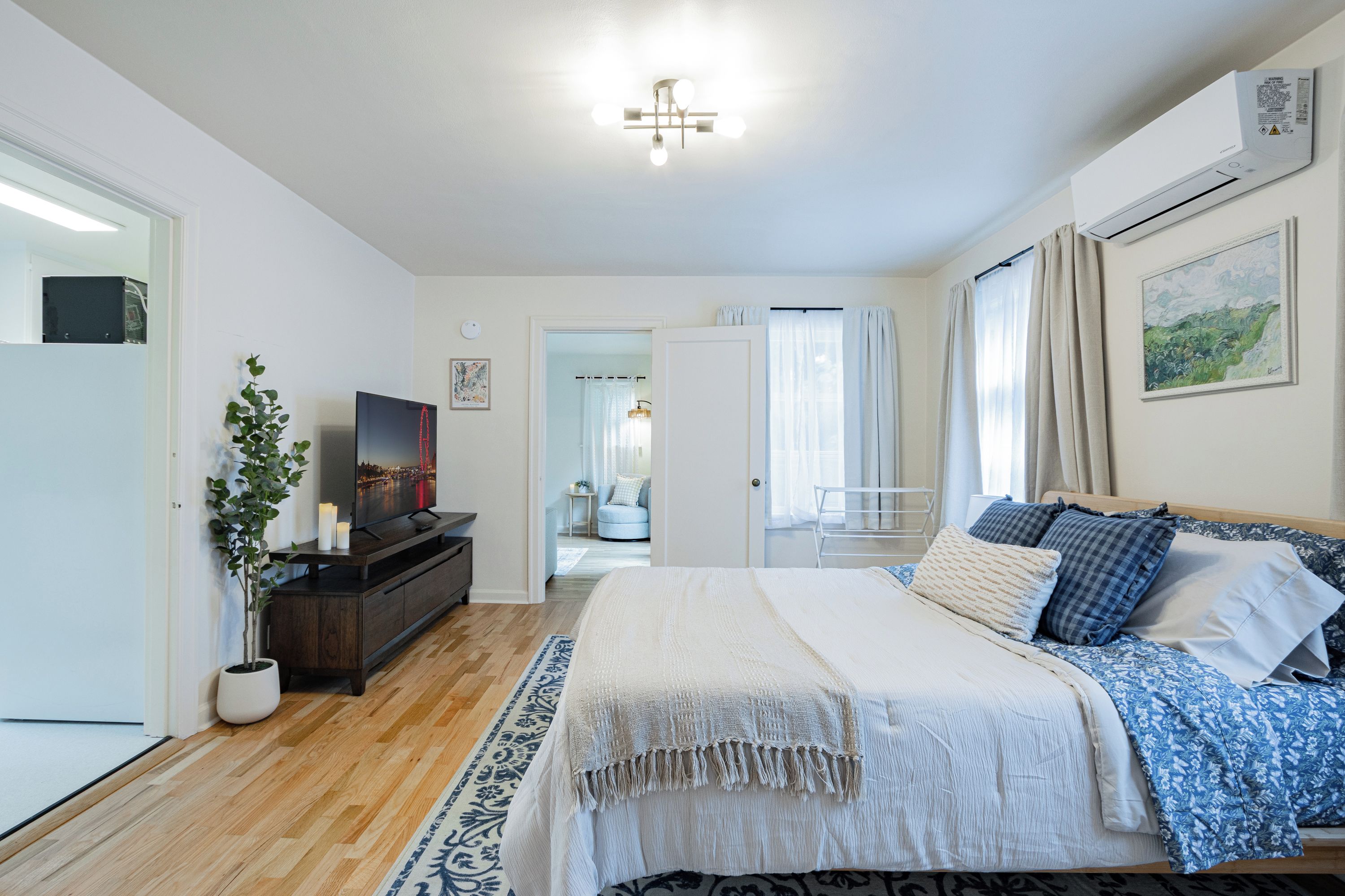 Une chambre à coucher moderne avec un lit, une table de chevet, un téléviseur et une plante en pot.
