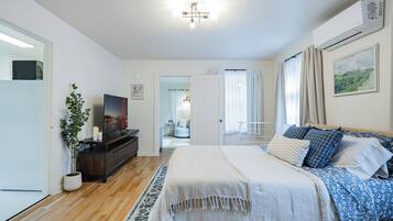 Une chambre à coucher moderne avec un lit, une table de chevet, un téléviseur et une plante en pot.