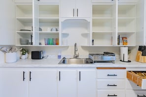 A modern kitchen with white cabinetry, a stainless steel sink, and a built-in dishwasher.
