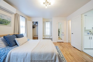 A bedroom with a bed, bedside tables, a wardrobe, and a bathroom visible through an open door.