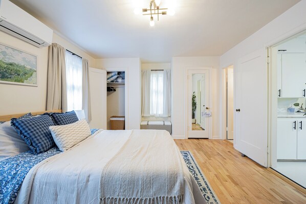 A bedroom with a bed, bedside tables, a wardrobe, and a bathroom visible through an open door.